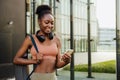 Young beautiful smiling fit afro woman with phone and mat Royalty Free Stock Photo