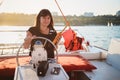 Young beautiful smiling girl in black shirt driving luxury yacht in sea with walkie-talkie in hands, sunset Royalty Free Stock Photo