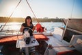 Young beautiful smiling girl in dress driving luxury yacht in sea with walkie-talkie in hands, summer evening Royalty Free Stock Photo