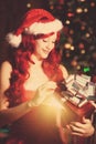 Young beautiful smiling santa woman near the Christmas tree with Royalty Free Stock Photo