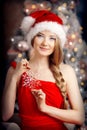 Young beautiful smiling santa woman near the Christmas tree. Fashionable luxury girl celebrating New Year. Beauty luxury trendy b