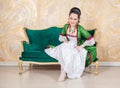 Beautiful smiling sensual woman in rococo style medieval dress sitting in the sofa Royalty Free Stock Photo