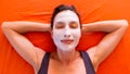 Young beautiful smiling woman with facial clay mask relaxing on the bed Royalty Free Stock Photo