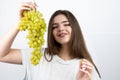 Young beautiful smiling woman holding bunch of green grapes standing on isolated white background dietology and nutrition