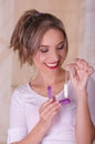Young beautiful smiling woman holding a menstruation cotton tampon in one hand and with her other hand a plastic purple