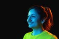 Young beautiful smiling woman isolated on dark background in neon light Royalty Free Stock Photo