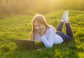 Young beautiful smiling woman with a laptop lies on the grass in Royalty Free Stock Photo