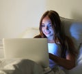 Young beautiful smiling woman lie in bed hold hands on laptop co Royalty Free Stock Photo