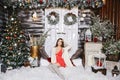 Young beautiful smiling woman near the Christmas tree. Beautiful luxury trendy brunette sits on stairs at Christmas Royalty Free Stock Photo