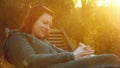 Young beautiful smiling woman relaxs on a deck-chair reading a book in sunset back light