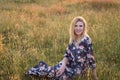 Young beautiful smiling woman sitting on grass in long dress Royalty Free Stock Photo