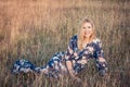 Young beautiful smiling woman sitting on grass in long evening dress Royalty Free Stock Photo