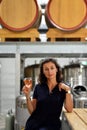 A young beautiful smiling woman sitting on a high chair and holding a glass of rose wine in a winery Royalty Free Stock Photo