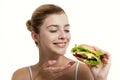 Young beautiful smilling girl holds a burger in hand