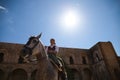 Young and beautiful Spanish woman riding on her brown horse, and wearing typical riding clothes. The woman has the sun on her back Royalty Free Stock Photo