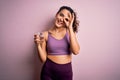 Young beautiful sportswoman with curly hair doing sport drinking glass of water with happy face smiling doing ok sign with hand on