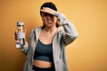 Young beautiful sportswoman doing sport wearing sportswear drinking bottle with water stressed with hand on head, shocked with Royalty Free Stock Photo