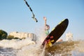 Young beautiful sporty girl in a green life jacket rides a wakeboard on a river or lake near city. Happy athlete girl Royalty Free Stock Photo