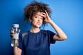 Young beautiful sporty woman with curly hair and piercing doing sport holding bottle of water stressed with hand on head, shocked Royalty Free Stock Photo