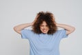 Young beautiful stressed curly woman with closed eyes holding head