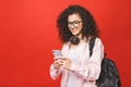 Young beautiful student curly woman with smart phone isolated over red background. Using phone Royalty Free Stock Photo