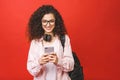 Young beautiful student curly woman with smart phone isolated over red background. Using phone Royalty Free Stock Photo