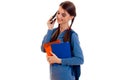 Young beautiful student girl with backpack posing and talks phone isolated on white background in studio Royalty Free Stock Photo