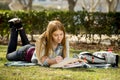 Young beautiful student girl on campus park grass with books studying happy preparing exam in education concept Royalty Free Stock Photo