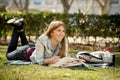 Young beautiful student girl on campus park grass with books studying happy preparing exam in education concept Royalty Free Stock Photo