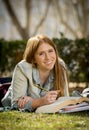 Young beautiful student girl on campus park grass with books studying happy preparing exam in education concept Royalty Free Stock Photo