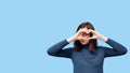 A young beautiful student girl in glasses makes a heart shape with her hands instead of eyes, smiles Royalty Free Stock Photo