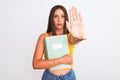 Young beautiful student girl holding notebook standing over isolated white background with open hand doing stop sign with serious Royalty Free Stock Photo