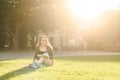 Young beautiful student girl sitting on campus park grass under the sunlight with books. Smiling female student studying and Royalty Free Stock Photo