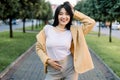 Young beautiful stylish Asian brunette girl, wearing in yellow jacket, white t-shirt and beige pants, walking and posing Royalty Free Stock Photo