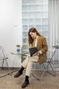 Young and beautiful stylish Asian woman sitting on chair and reading magazine in relax conner of modern office or cafe. Royalty Free Stock Photo