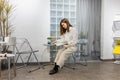 Young and beautiful stylish Asian woman sitting on chair and reading magazine in relax conner of modern office or cafe. Royalty Free Stock Photo