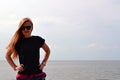 Young beautiful stylish girl in a simple black t-shirt posing near the sea Royalty Free Stock Photo