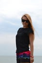 Young beautiful stylish girl in a simple black t-shirt posing near the sea Royalty Free Stock Photo