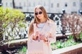 Young beautiful stylish girl walking and posing in white dress and pink coat in city . Outdoor summer portrait of young classy wom Royalty Free Stock Photo