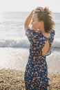 Woman in blue dress posing at beach on sunset.