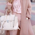 Young beautiful stylish woman walking in a pink coat, holding a bag in hands, street style, spring autumn trend Royalty Free Stock Photo