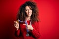 Young beautiful succesful woman with curly hair and piercing winning medals very happy pointing with hand and finger