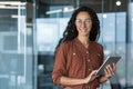 Young beautiful and successful business woman with tablet computer and glasses, smiling and looking out the window Royalty Free Stock Photo