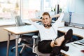 Young beautiful successful businesswoman resting, relaxing at workplace, over office background. Royalty Free Stock Photo