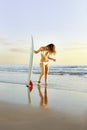 Young beautiful surfer girl standing on beach with surfboard Royalty Free Stock Photo