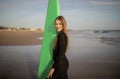 Young beautiful surfer woman with surfboard posing on sandy beach at sunset Royalty Free Stock Photo