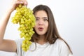 Young beautiful surprised woman standing with bunch of green grapes standing on isolated white background dietology and nutrition