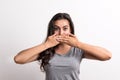 Young beautiful woman standing in a studio in studio, covering mouth with hands. Royalty Free Stock Photo