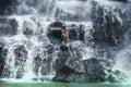 Young beautiful and sweet Asian woman in bikini getting body wet under stream of natural amazing waterfall sitting on rock feeling Royalty Free Stock Photo