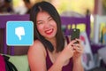 Young beautiful and sweet Asian woman with mobile phone in her hand composed with unlike icon using internet app in social media